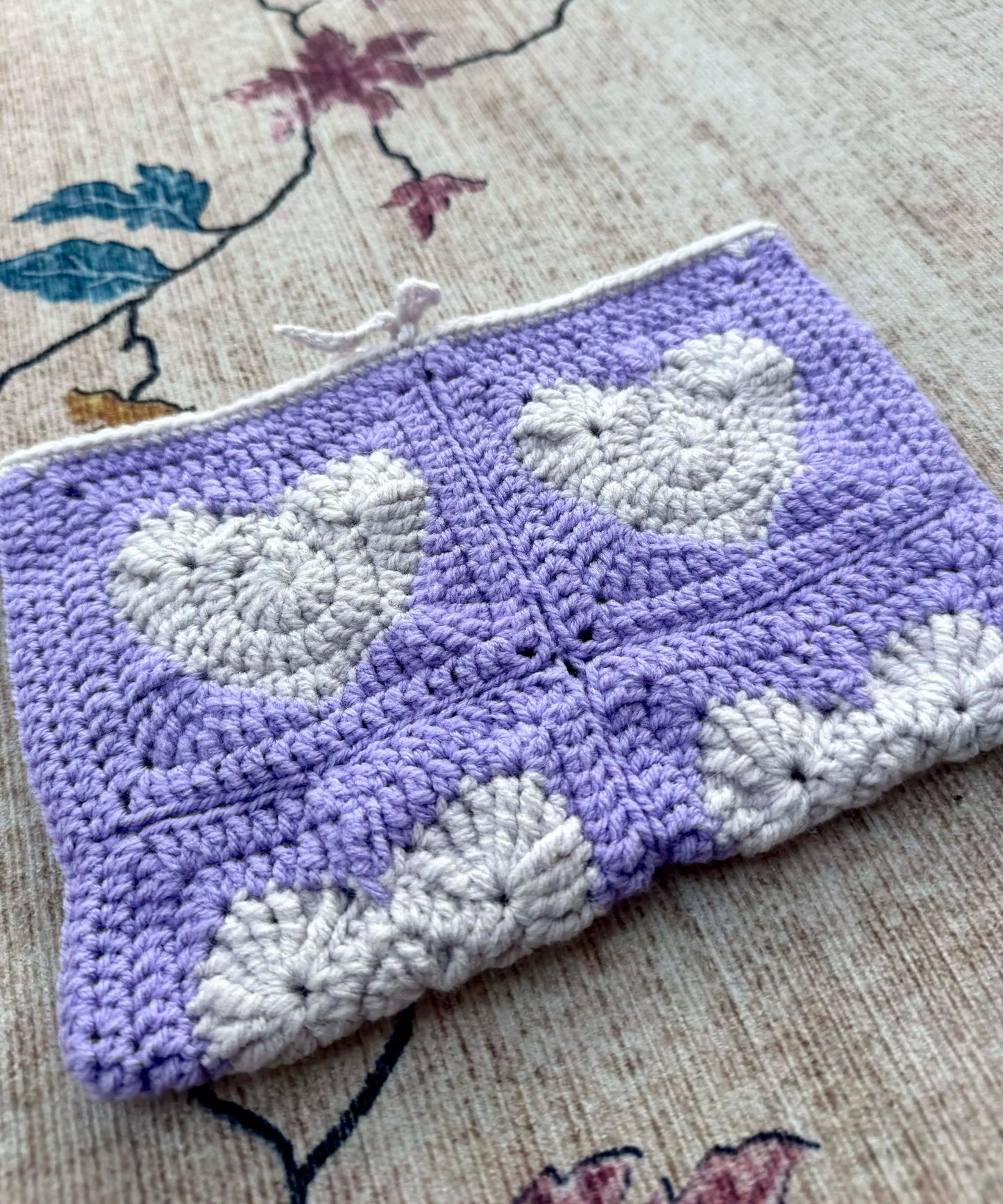 Crocheted book cover with a heart pattern on a textured surface