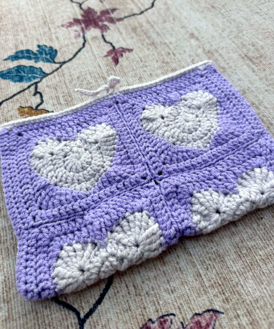 Crocheted book cover with a heart pattern on a textured surface