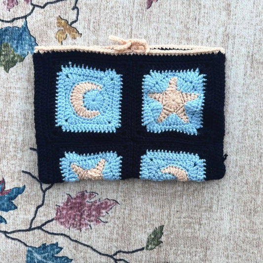 Crocheted book cover with star and moon designs on a floral fabric background