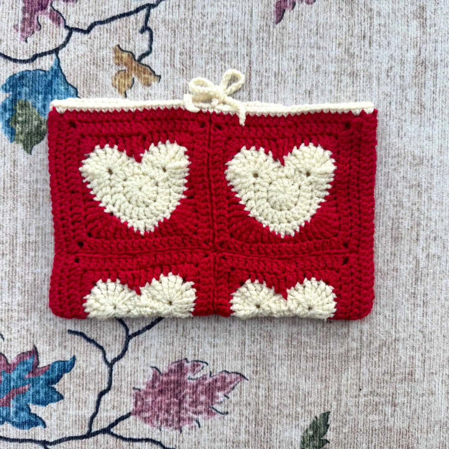 Crocheted book cover with heart patterns on a floral fabric background