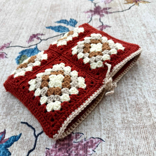 Crocheted book cover with a floral pattern on a floral fabric background