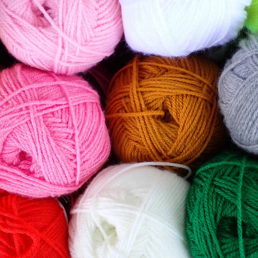 Assorted colourful yarn balls on a dark background.