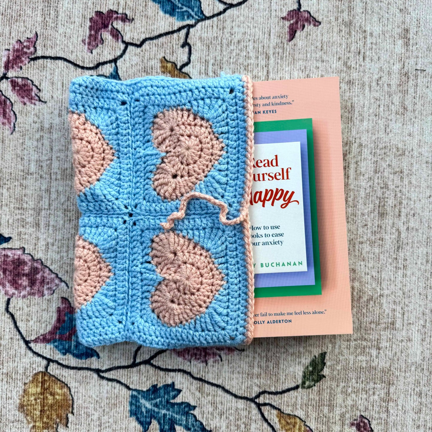 Crocheted blue and pink book cover with a book titled 'Read Yourself Happy'.