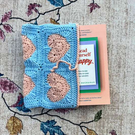 Crocheted blue and pink book cover with a book titled 'Read Yourself Happy'.