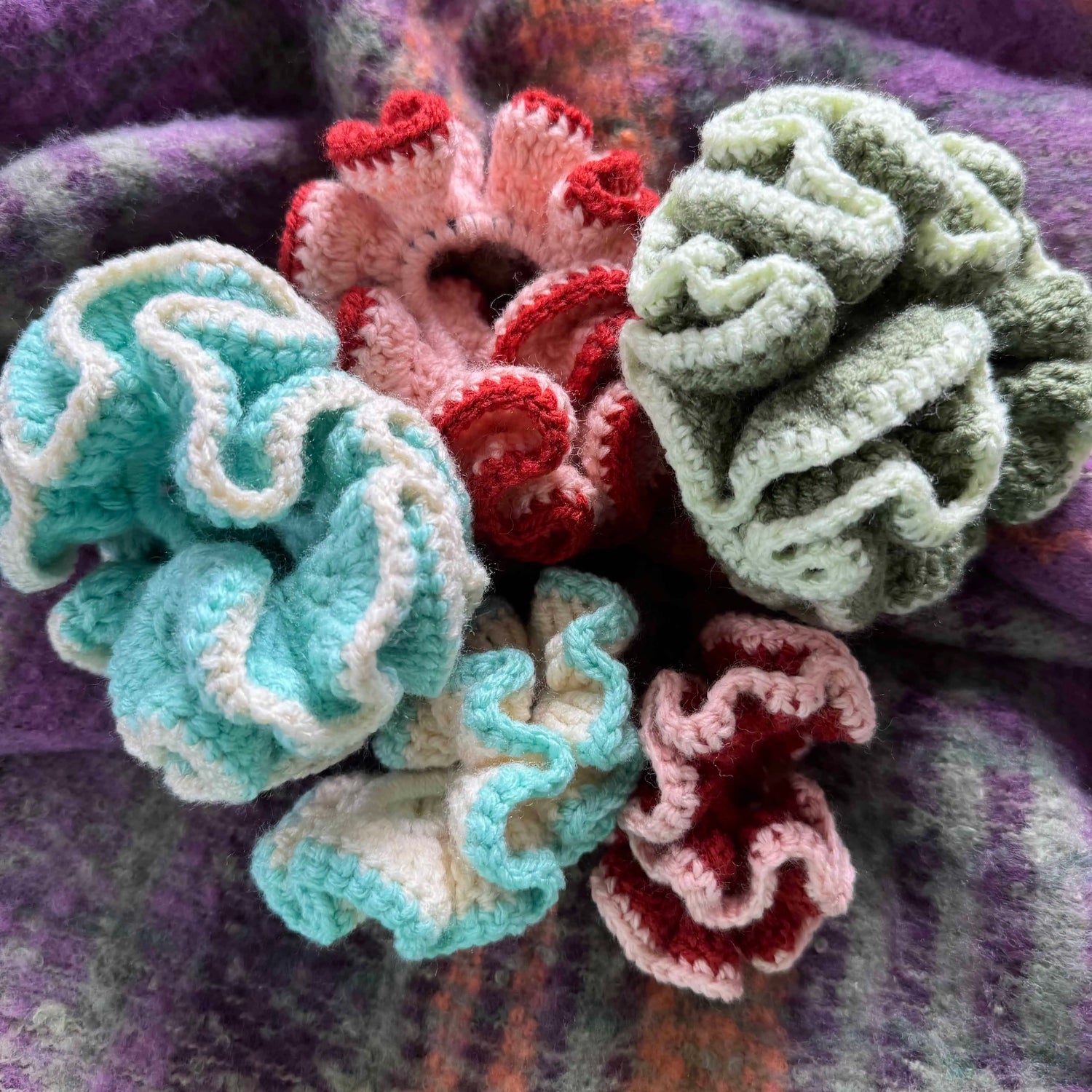 Colorful crocheted scrunchies on a textured fabric background