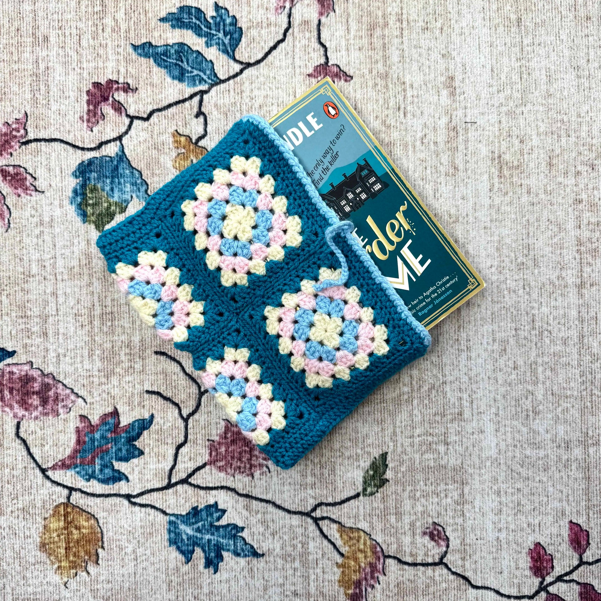 Crocheted book cover with floral patterns on a textured fabric background