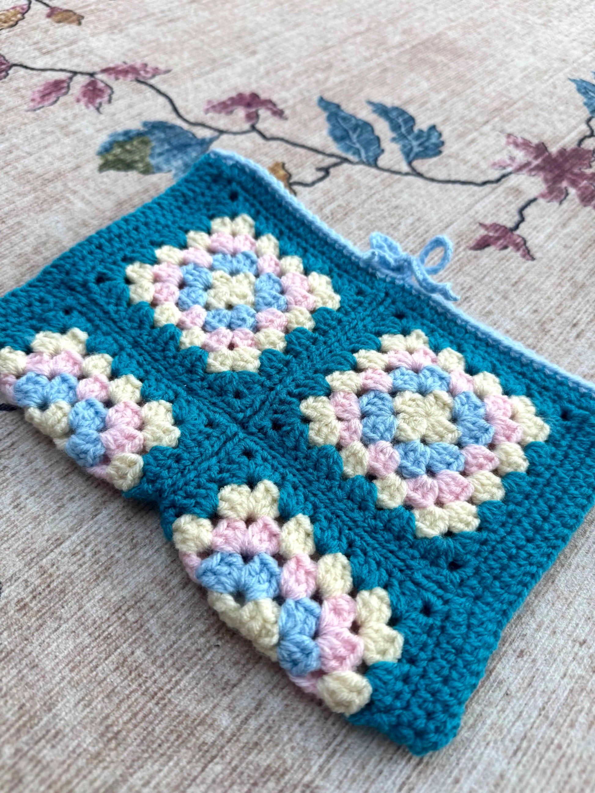 Crocheted book cover with a floral pattern on a textured surface