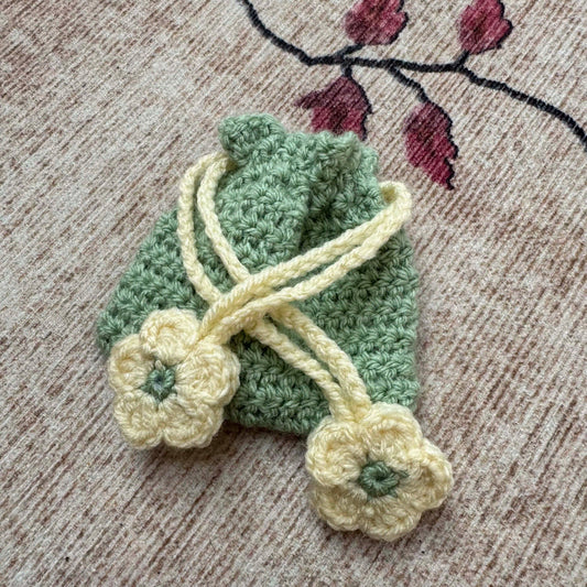Crocheted green bag with white flowers on a textured surface