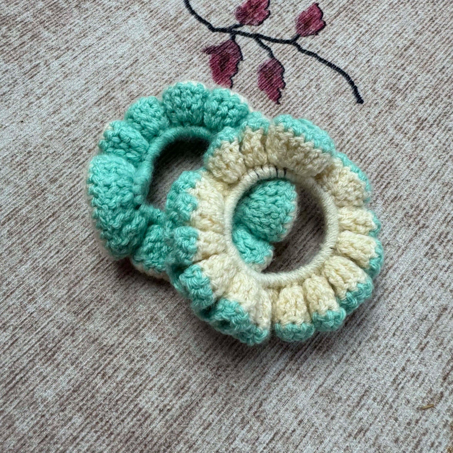 Two crocheted scrunchies, one green and one cream.
