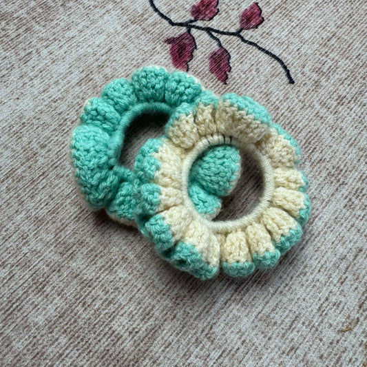 Two crocheted scrunchies, one green and one cream.