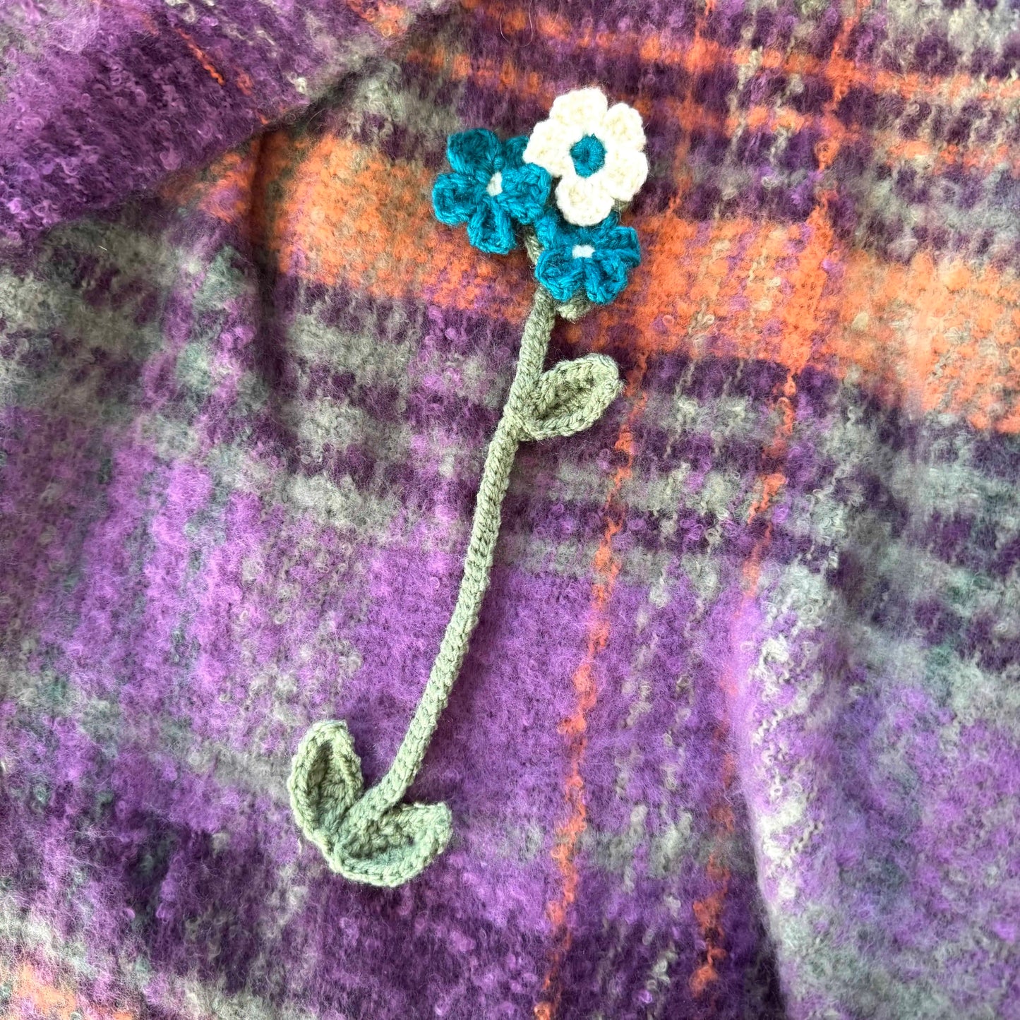 Crocheted flower bookmark on a plaid fabric background