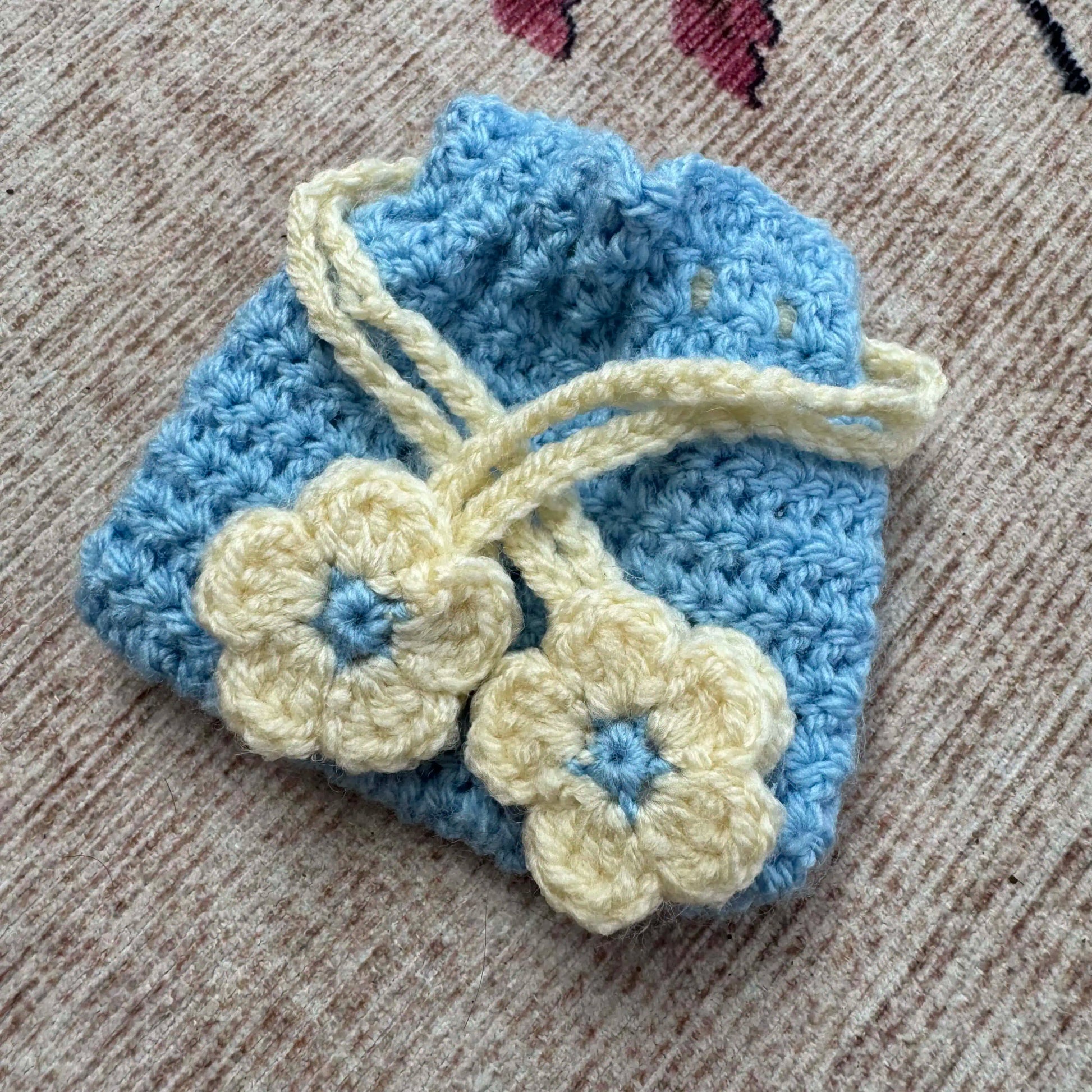 Blue and cream crocheted item with flowers on a textured surface