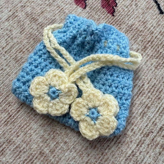 Blue and cream crocheted item with flowers on a textured surface