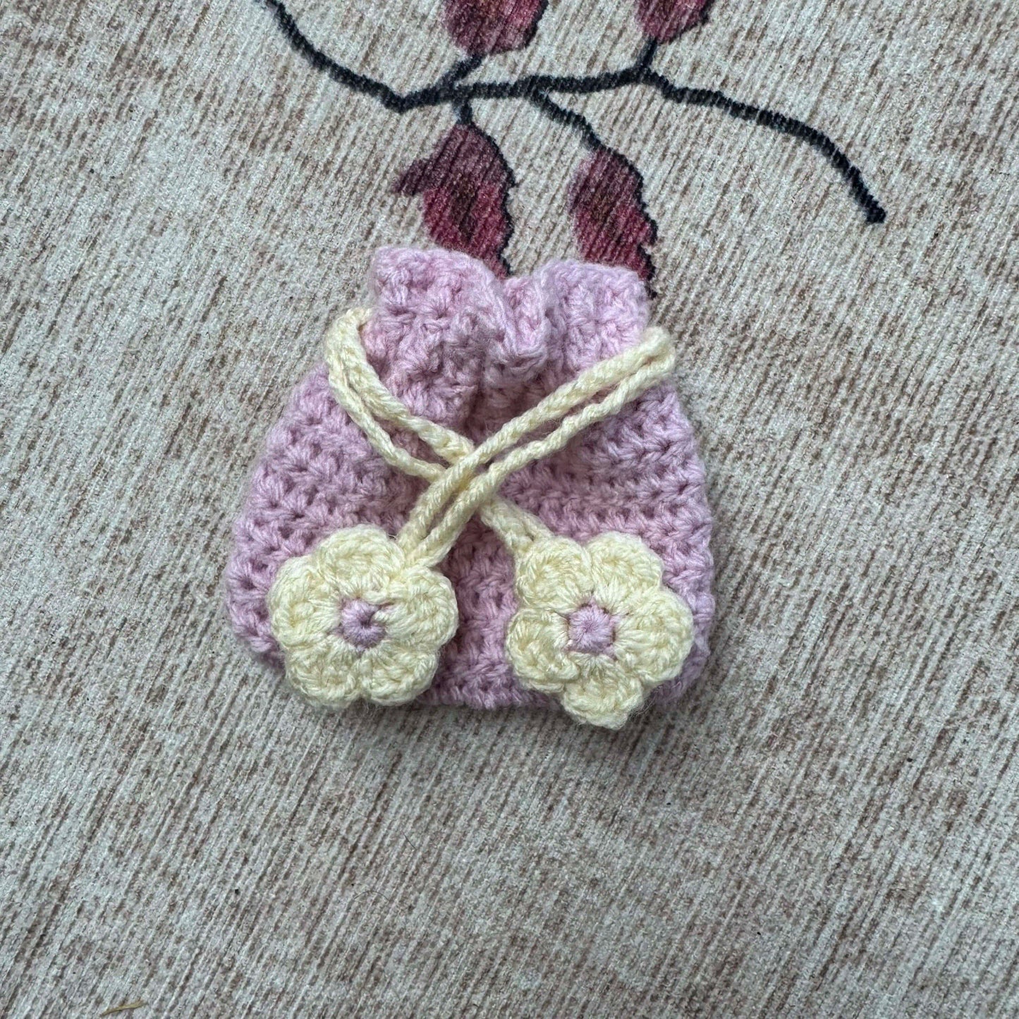 Small crocheted bag with floral details on a textured surface
