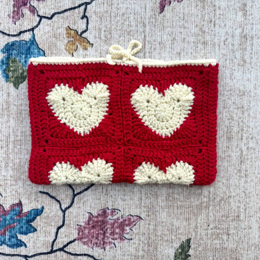 Crocheted book cover with heart patterns on a floral fabric background