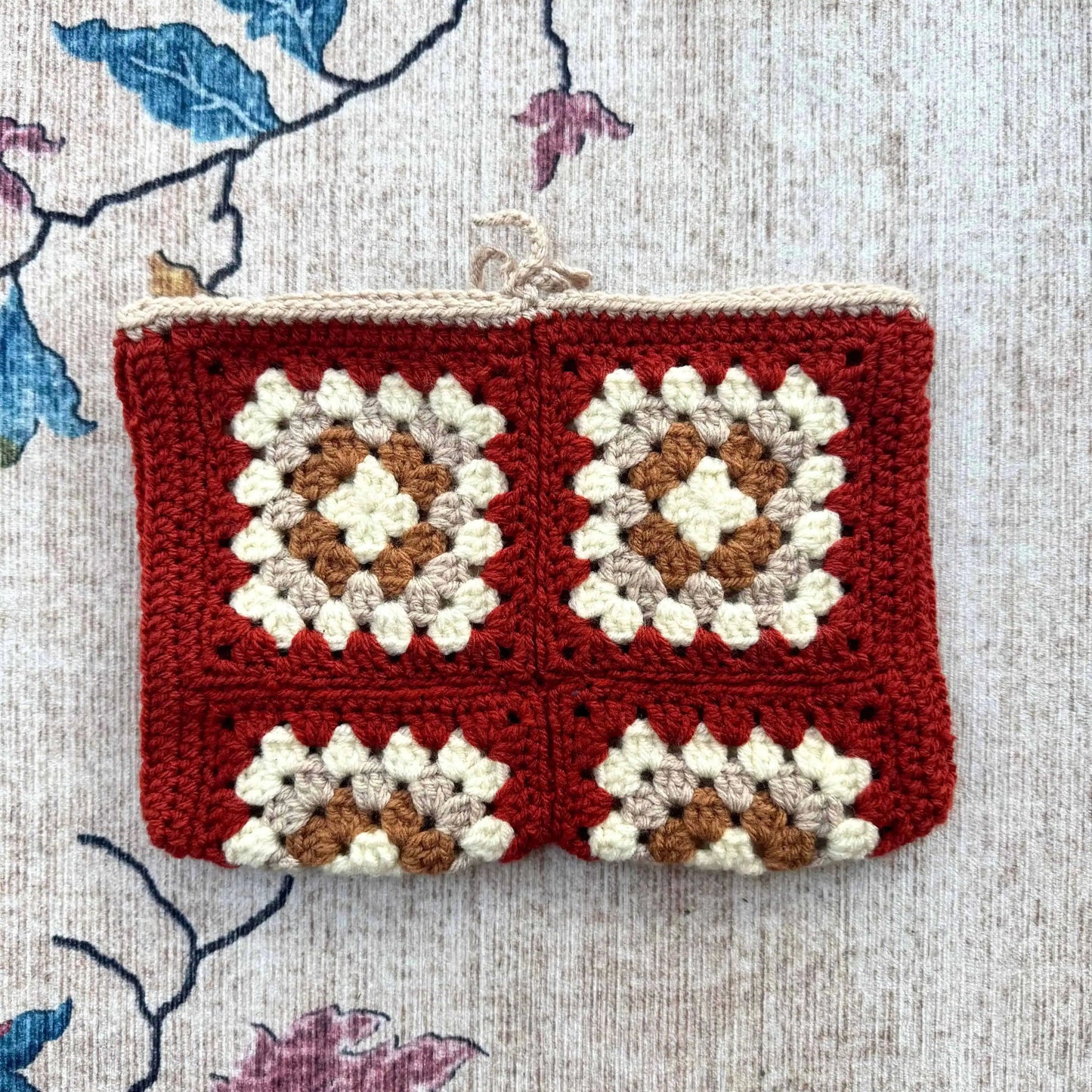 Crocheted book cover with a square pattern on a floral fabric background