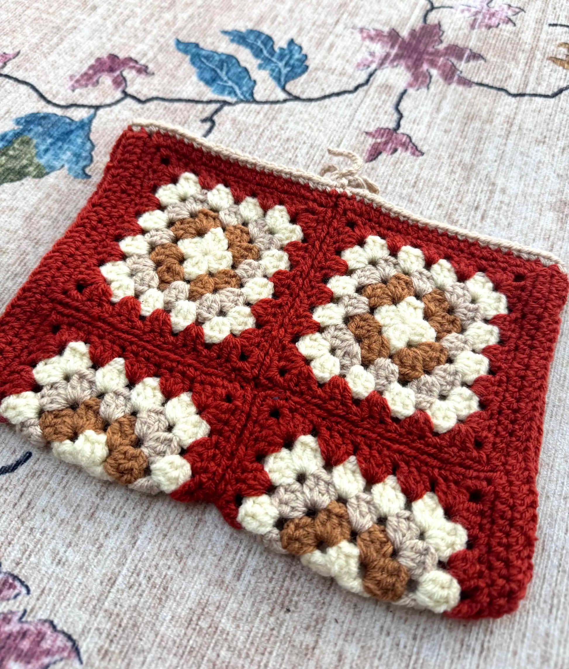 Crocheted book cover with a geometric pattern on a floral background