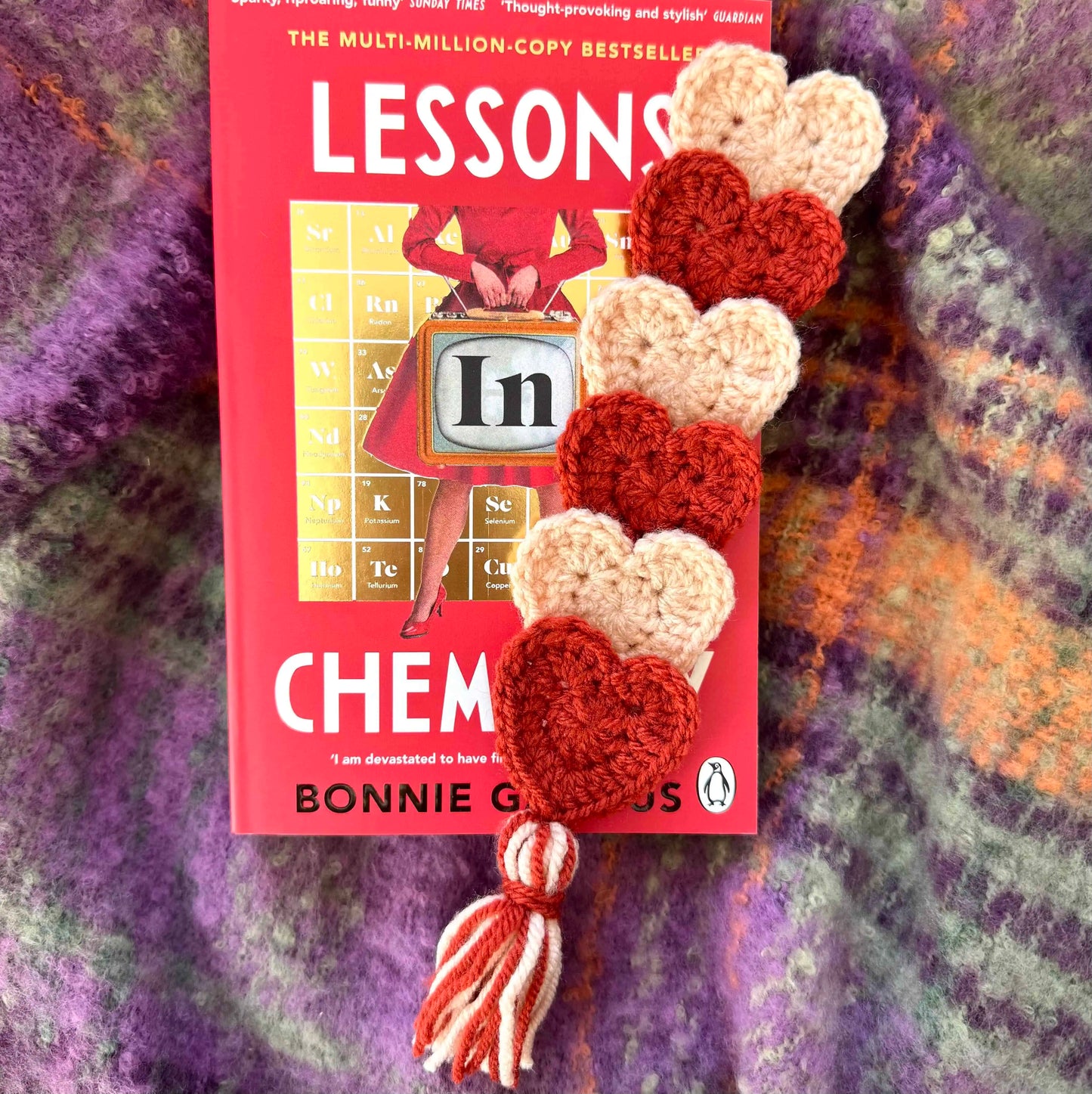 Crocheted heart bookmark on a textured fabric background.
