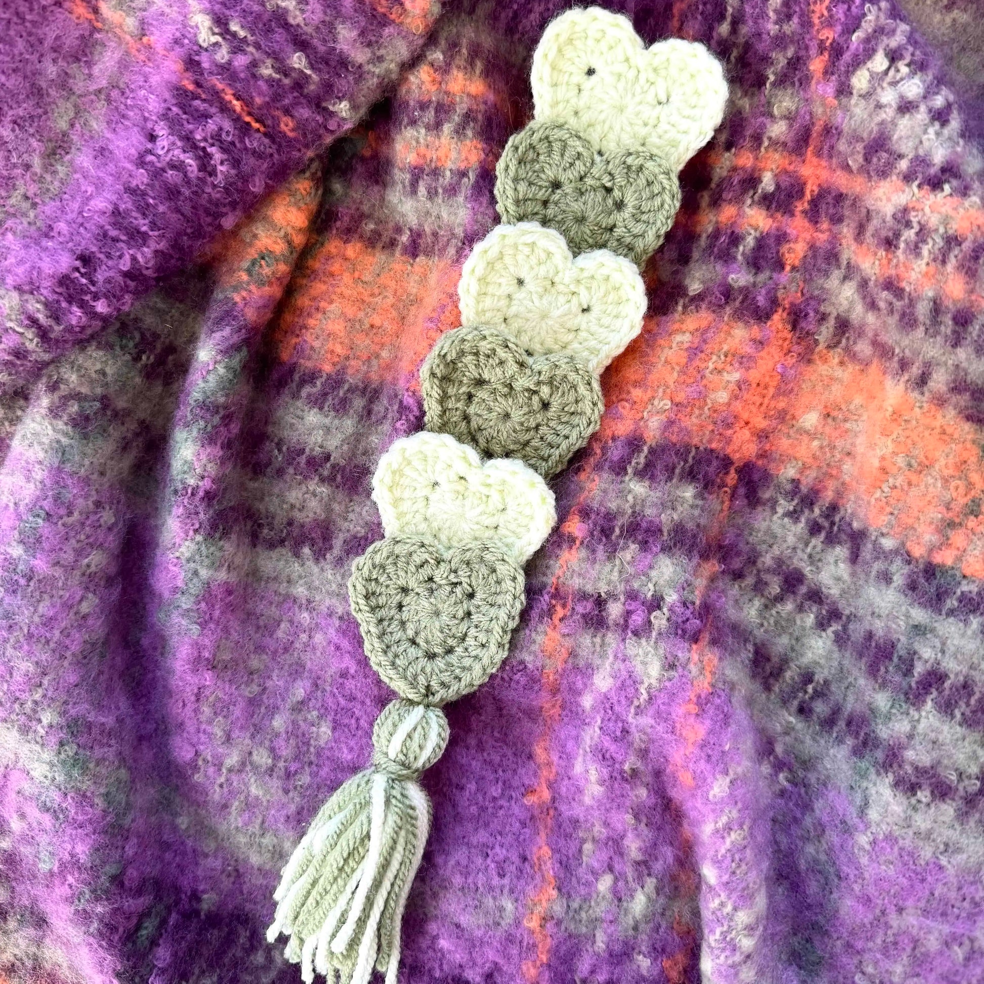 Crocheted heart-shaped bookmark on a purple plaid fabric background