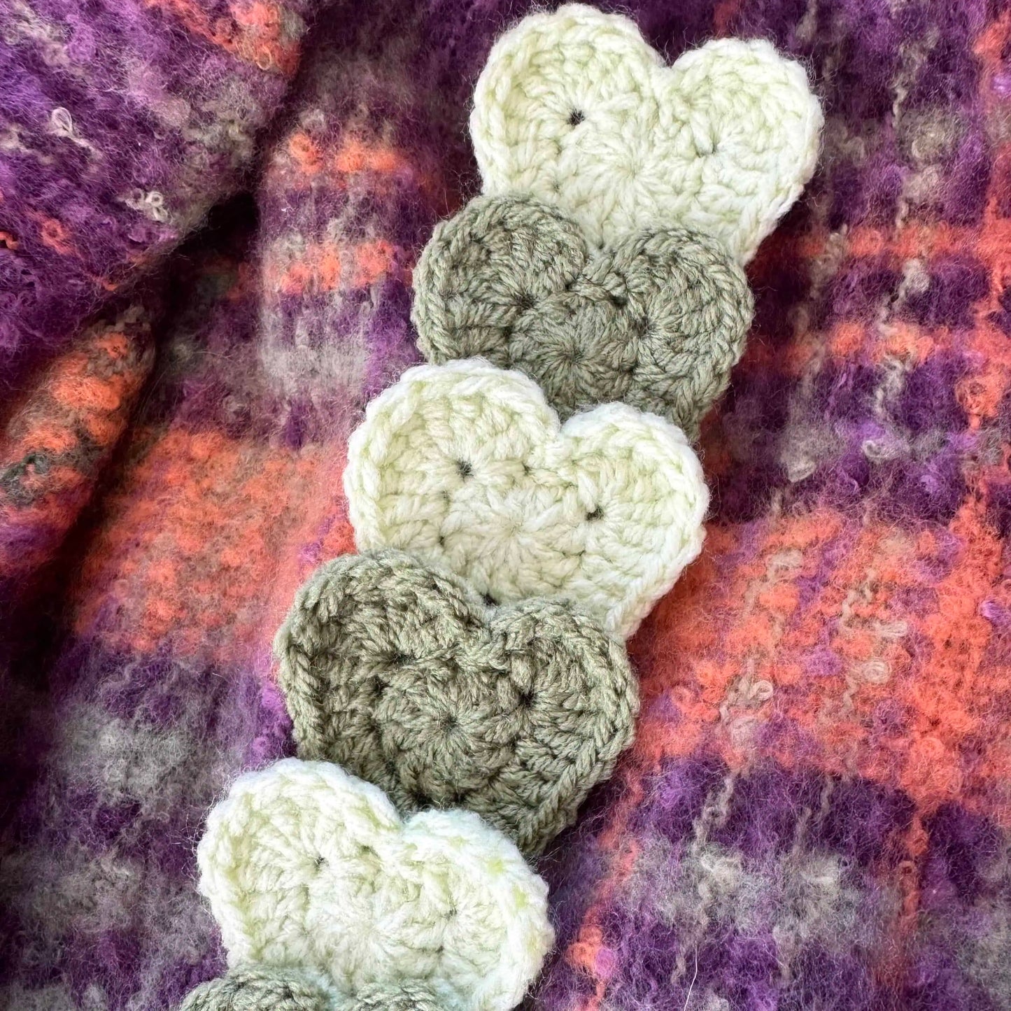 Crocheted heart bookmark on a textured fabric background