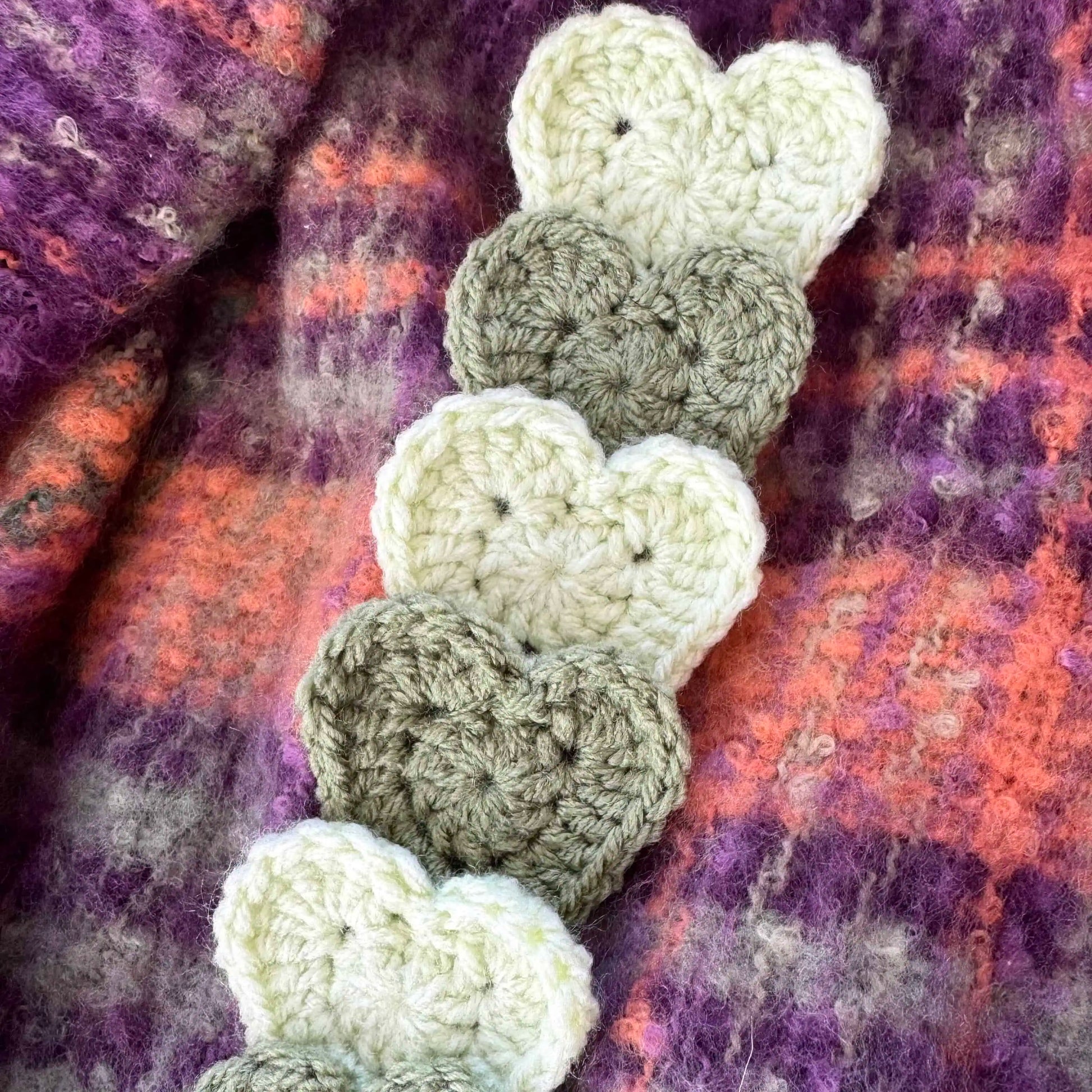 Crocheted heart bookmark on a textured fabric background